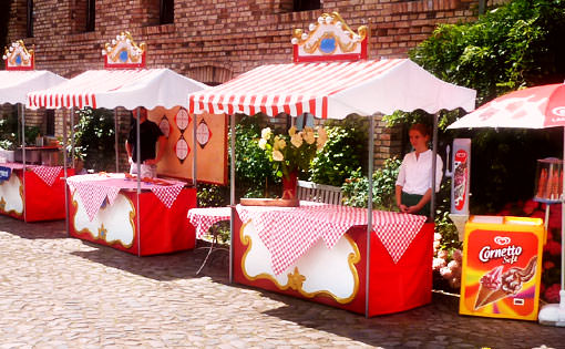 Nostalgische Marktstände mit Speisen, Getränken und Spielen auf einer Veranstaltung.